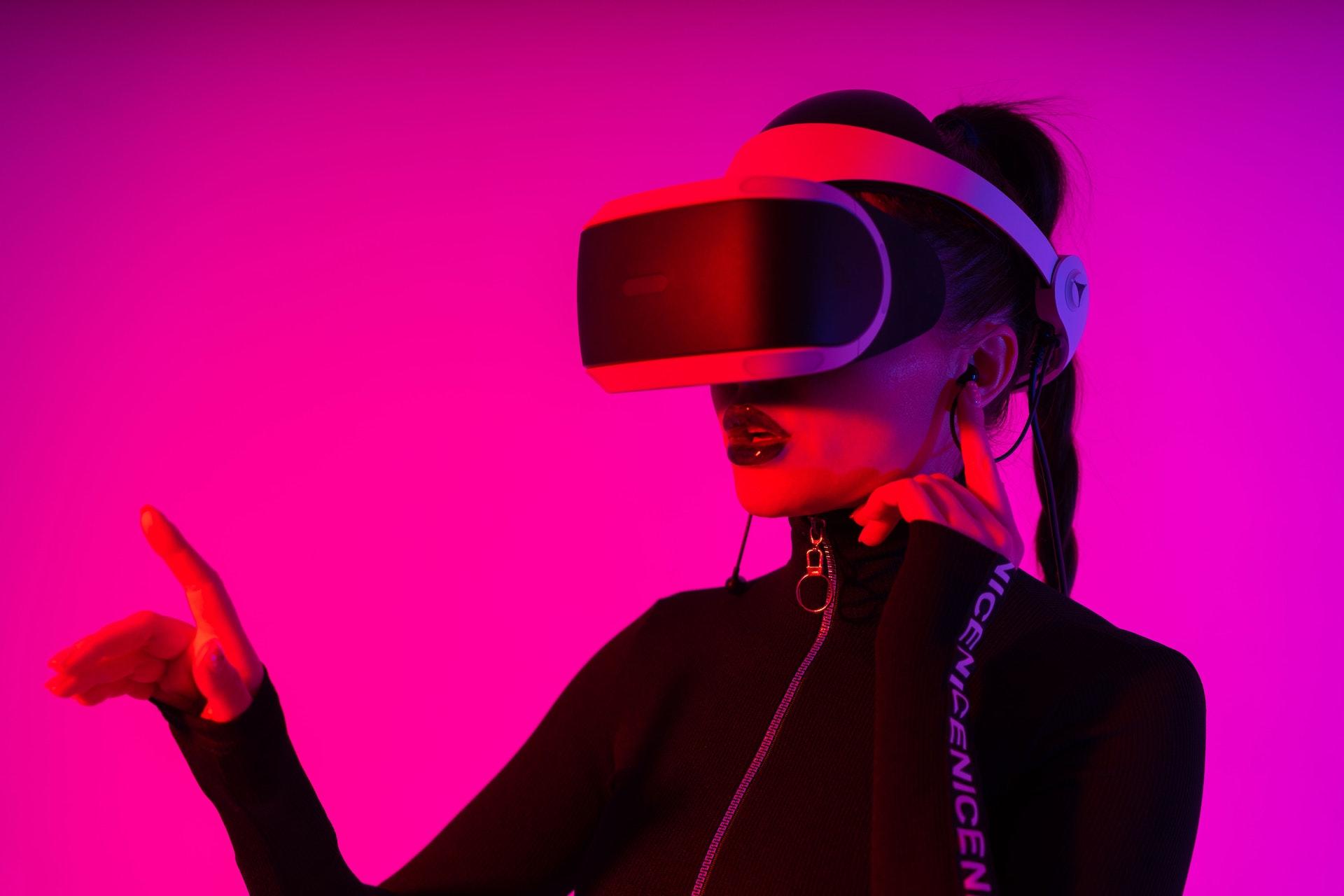 A gamer wearing a VR headset against a bright pink background.