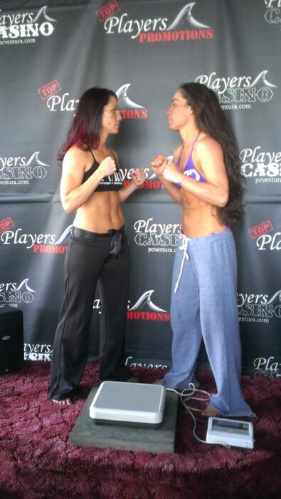 Two women facing off before a boxing match, wearing sports bras and sweatpants.