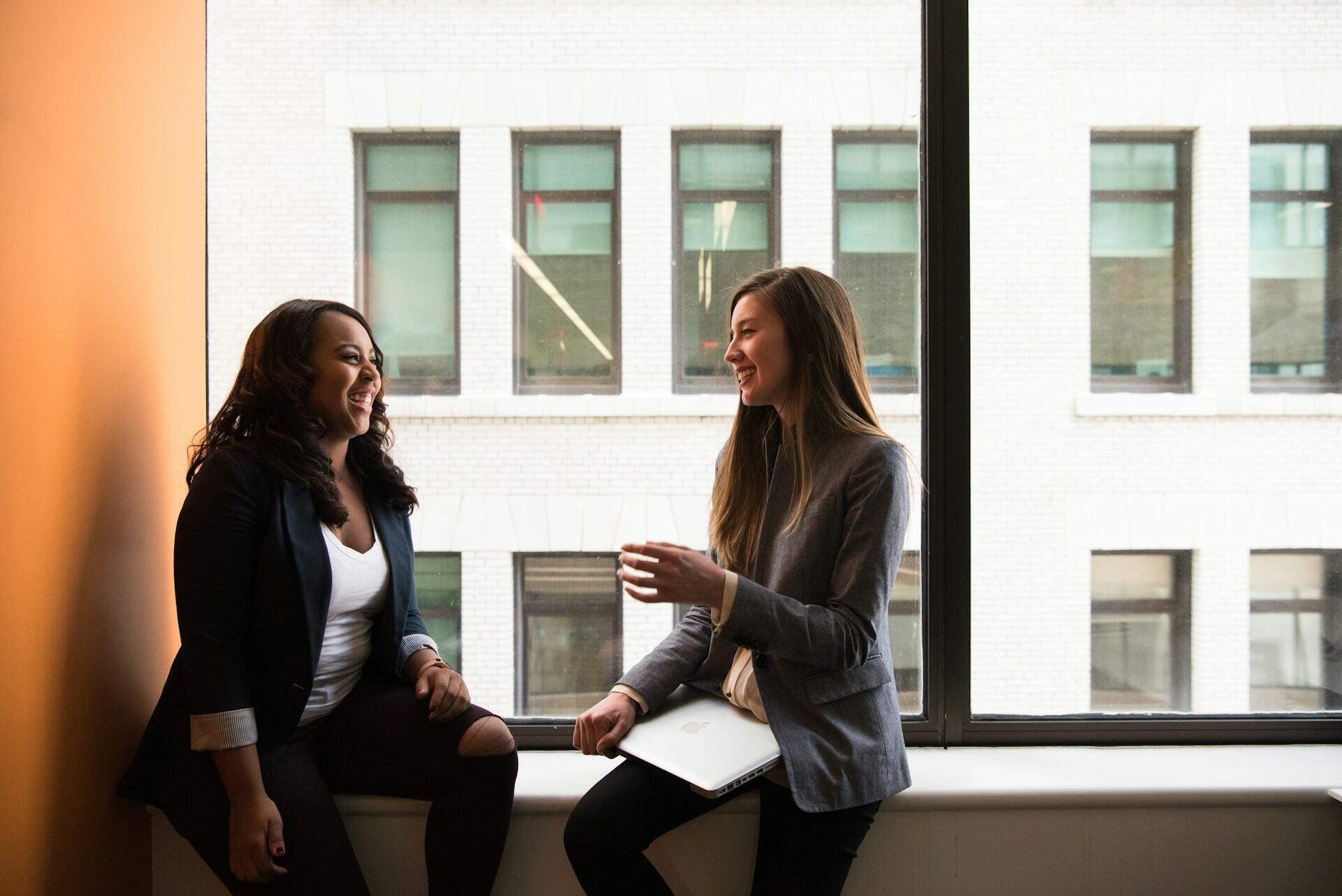 Two coworkers making small talk in an office setting
