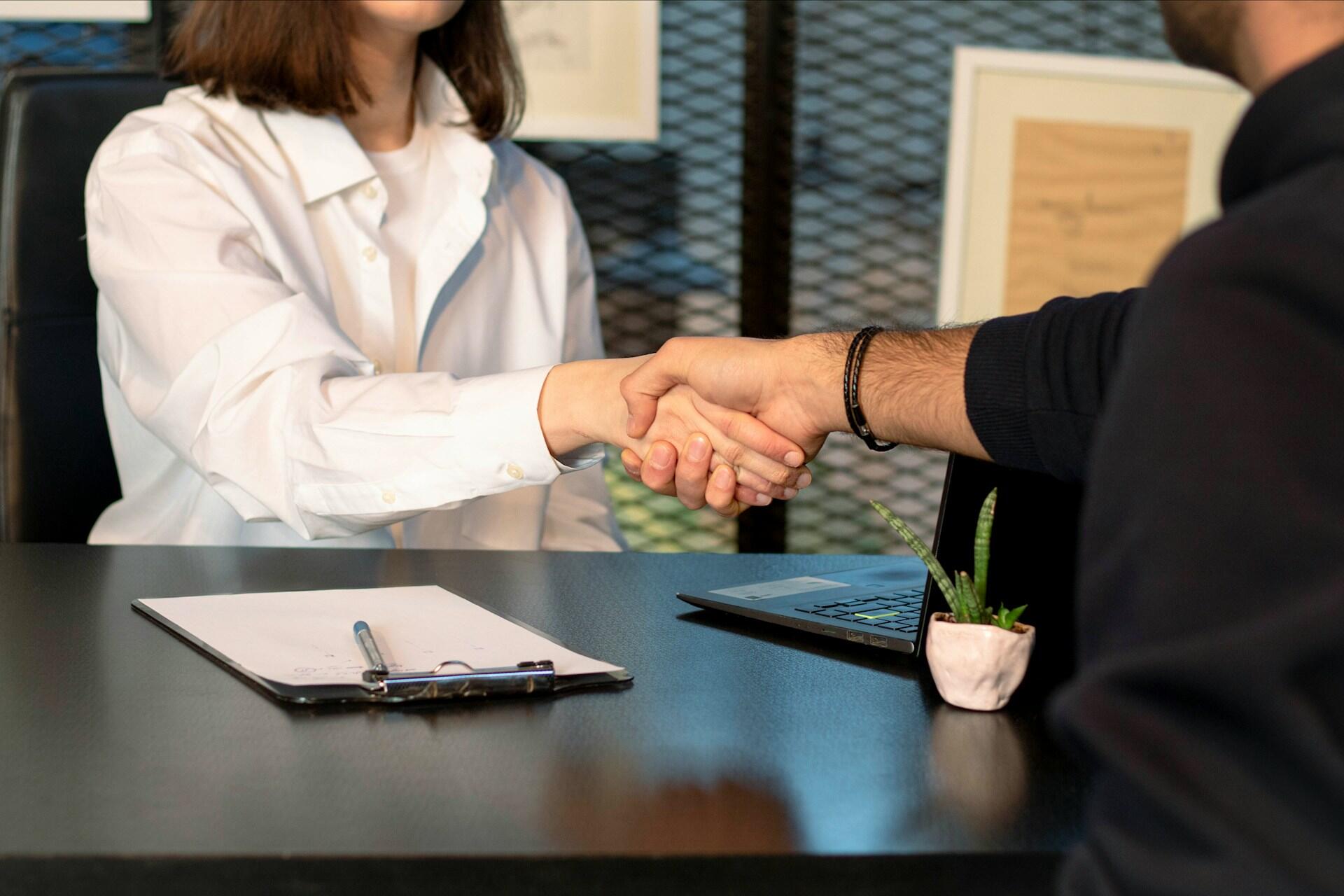 Two professionals shaking hands and making eye contact during a first introduction in an office setting
