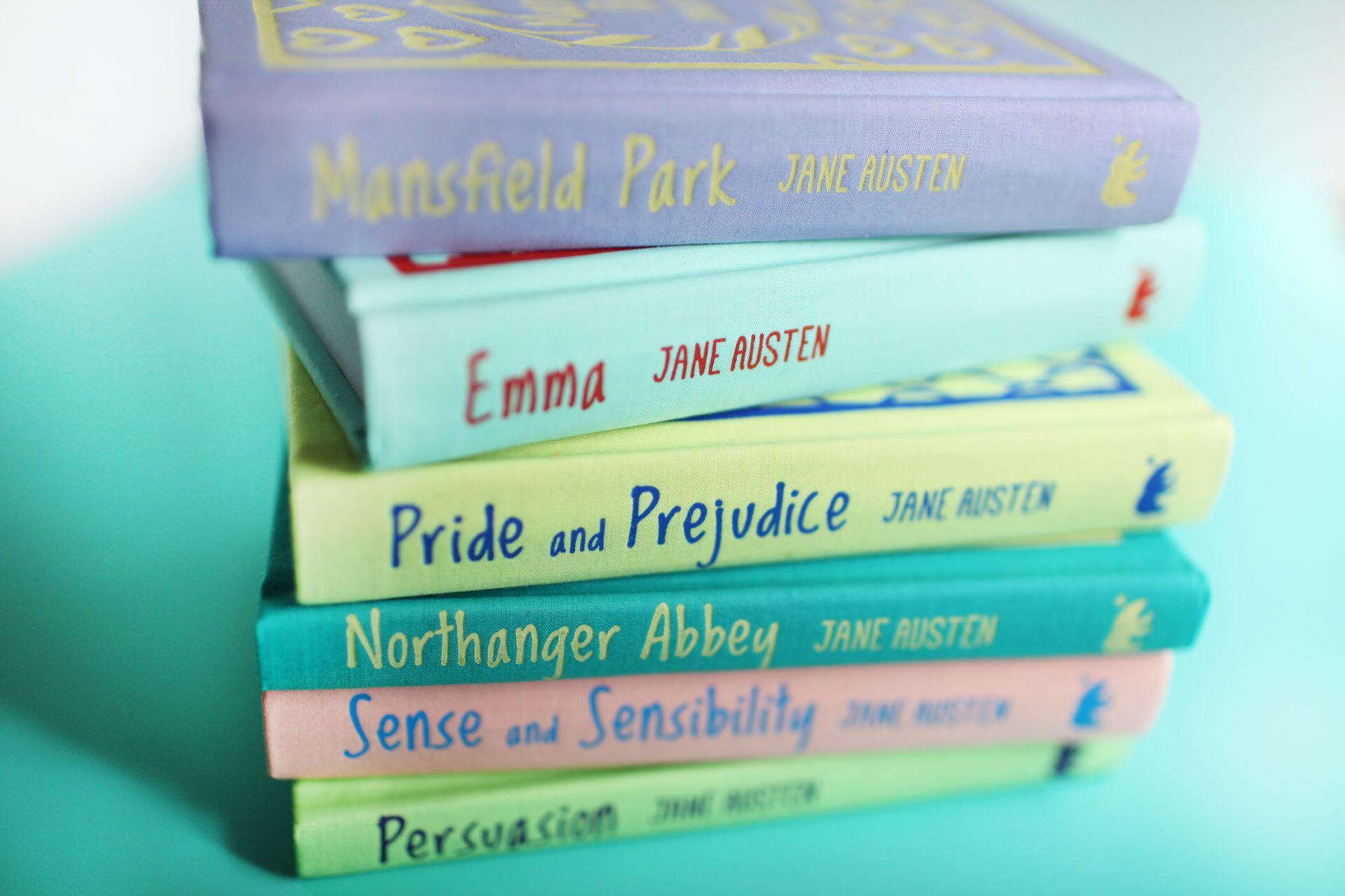A stack of colorful Jane Austen novels, including Mansfield Park, Emma, Pride and Prejudice, Northanger Abbey, Sense and Sensibility, and Persuasion.